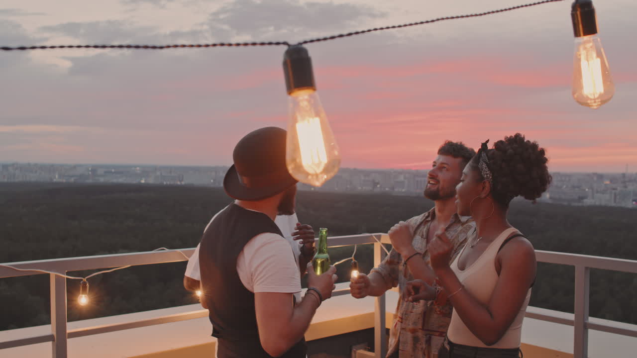 Giovani amici che ballano su una terrazza panoramica la sera