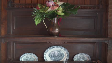 Close-up-of-decorative-plates-and-vase-with-flowers-on-an-old-wooden-cabinet