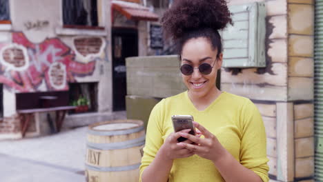 mujer elegante enviando mensajes de texto en el teléfono urbano