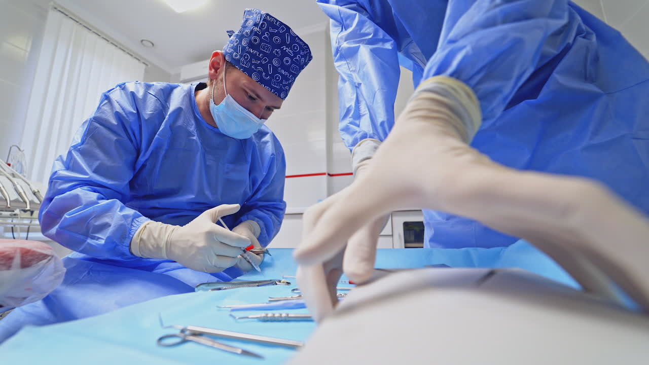 Doctor and assistant with dental instruments. Dentist in mask prepares medical tools before work. Medical equipment on the table.