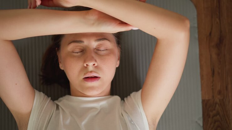 Tired woman lies on mat after training. Exhausted lady breathes out resting on floor in domestic gym. Pretty sportswoman with closed eyes at workout break