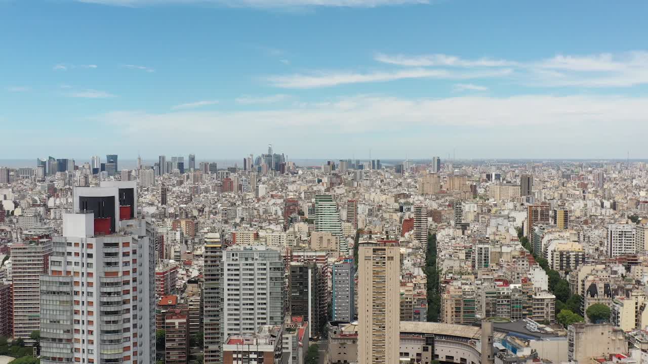 el avión no tripulado se eleva sobre el parque de las heras, revelando la vasta extensión urbana de buenos aires con puerto madero en el horizonte