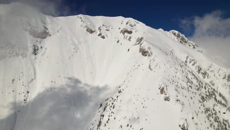 Snow-covered-La-Om-Peak-in-the-Piatra-Craiului-Mountains-under-a-clear-blue-sky,-aerial-view