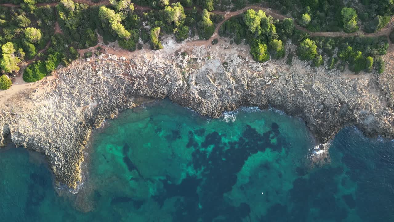 vista de arriba hacia abajo de la costa rocosa con playa cristalina cerca de sa coma, mallorca, españa