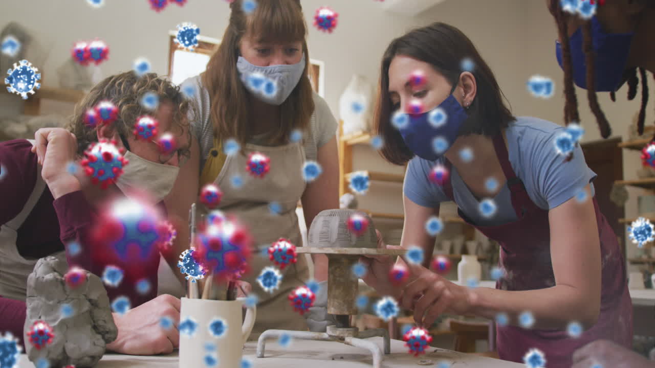 코로나 19 세포의 애니메이션은 얼굴 마스크를 착용하여 도자기 스튜디오에서 일하는 남자와 여자 위에 있습니다.