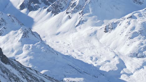 Deep-snow-on-the-sunlit-mountain-walls-in-the-Alps-of-Tyrol,-Austria---pan-view