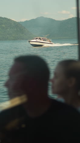 young couple relaxes on vacation on sailing boat overlooking picturesque hills against moving powerboat. enjoyment of relaxation and entertainment for tourists in summer