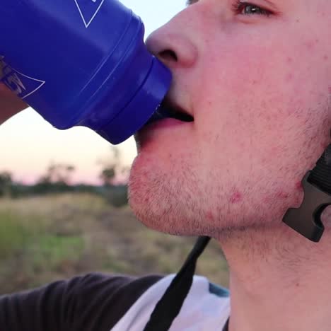 un garçon portant un casque regarde au loin tout en buvant dans une bouteille d'eau au ralenti