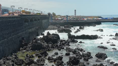 city of puerto de la cruz and rocky coastline with splashing waves