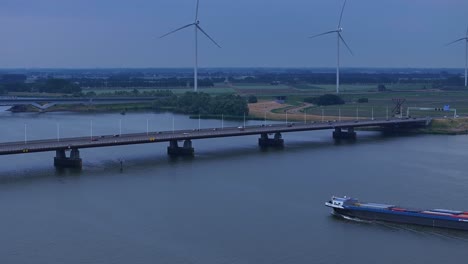 cargo vessel cruising in the hollands diep river towards the moerdijk bridges with wind turbines in the distance in netherlands