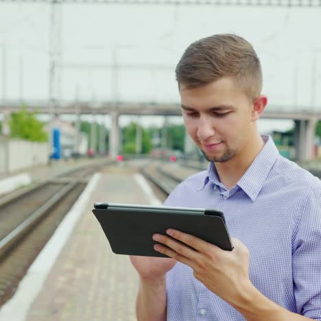 young man uses a tablet at a train station