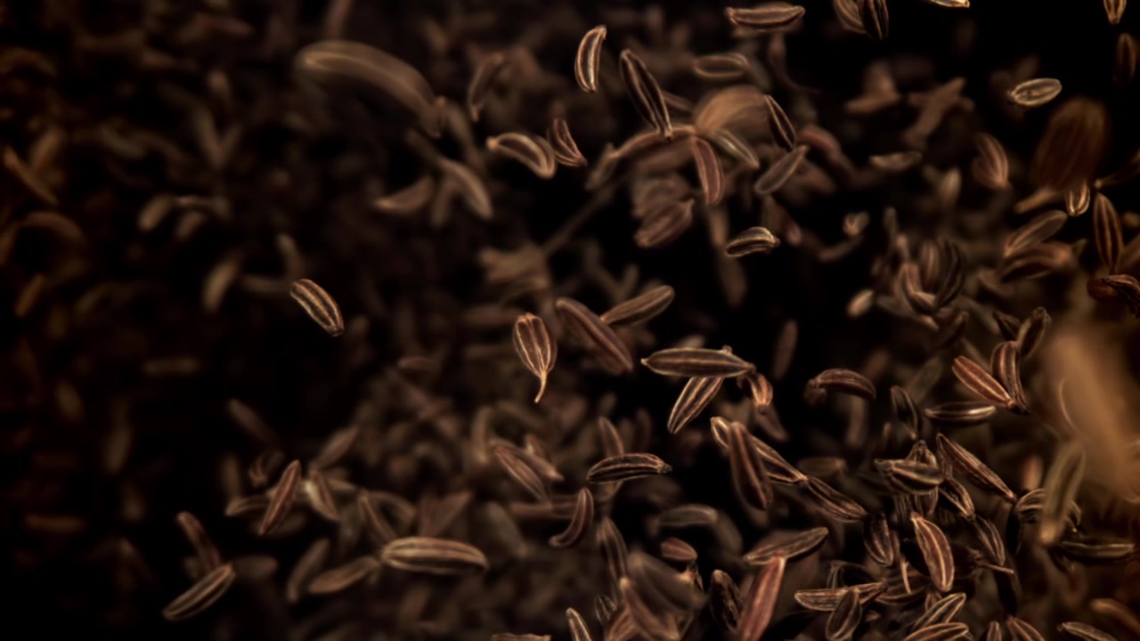 Cumin Seeds Falling in Slow Motion on a Dark Background