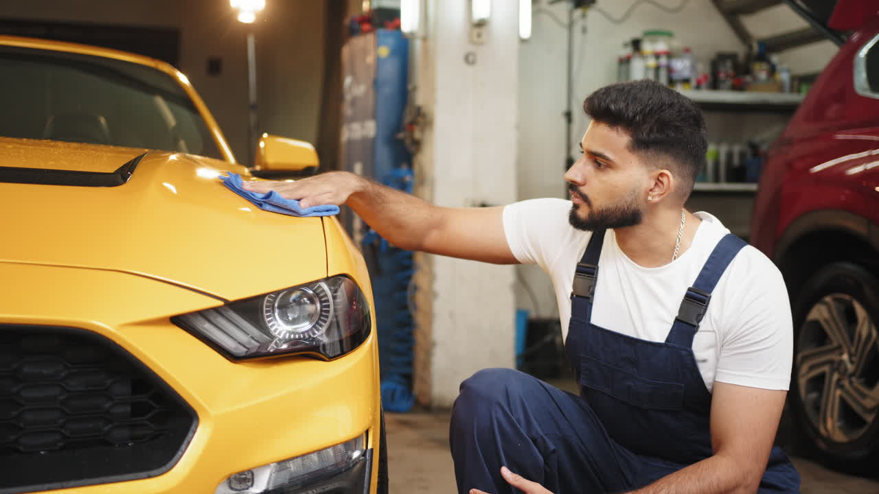 차고에서 노란색 스포츠카를 세부적으로 설명하는 남자