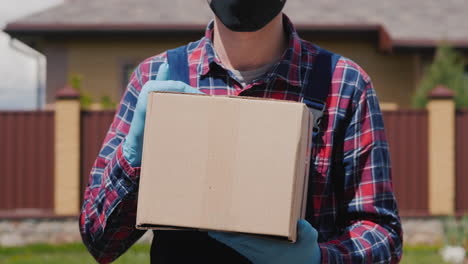 Der-Bote-In-Den-Handschuhen-Hält-Eine-Kiste-Mit-Einem-Paket