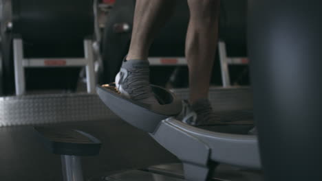 Schieben-Sie-Die-Füße-Eines-Mannes-Auf-Einem-Ellipsentrainer-Im-Fitnessstudio-Ein,-Stabilisierte-Aufnahme-In-Uhd-4k