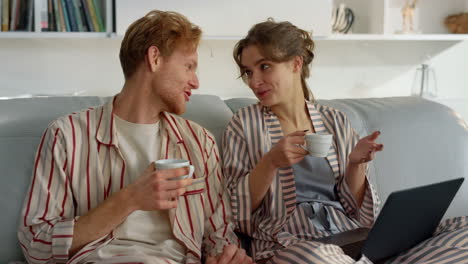 una joven pareja disfruta de un café en un cómodo sofá de cerca. tiempo de ocio matutino en casa