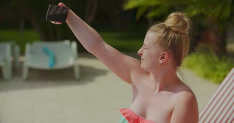 young lady sitting on beach while using her mobile device