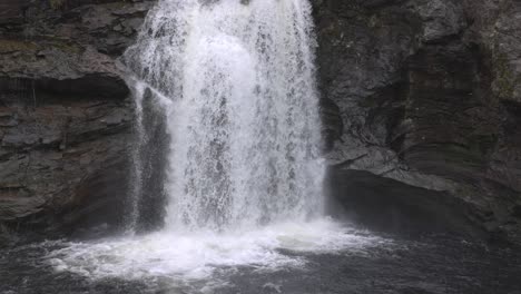 slow motion tilting shot establishing the falls of falloch flowing and splashing