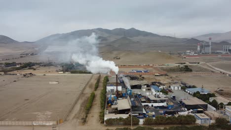 Drone-orbits-around-a-factory-chimney-with-smoke-plume-rising-up