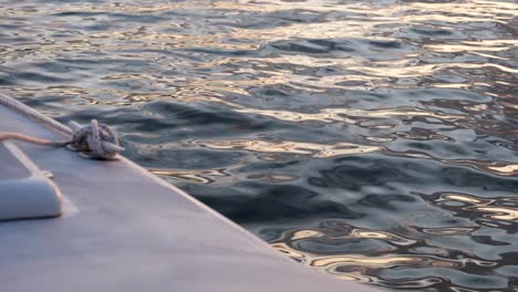 Slow-motion,-water-rippling-on-the-ocean-off-the-edge-of-a-sailboat