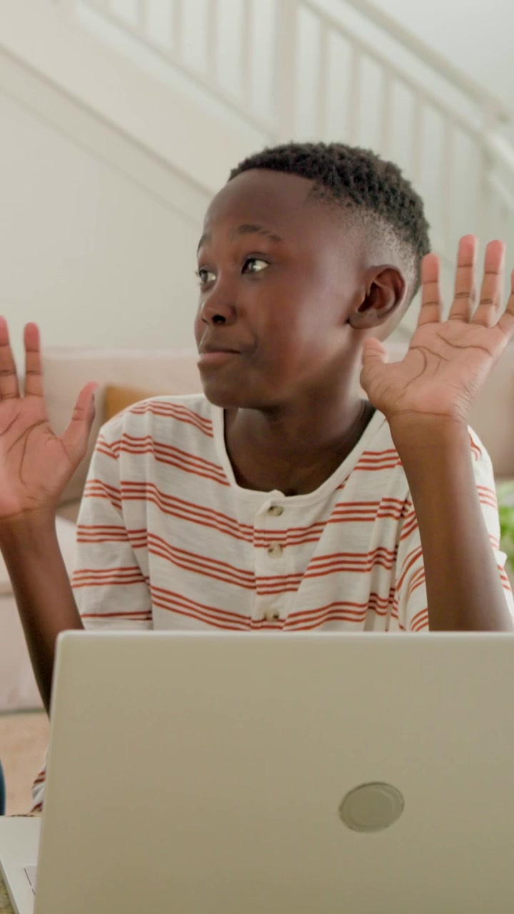 Vertical video: Seeing teen in striped shirt reacting to father guiding at counter typing on laptop