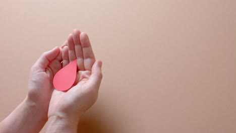 manos de una mujer caucásica tomando una gota de sangre en un fondo beige con espacio de copia, cámara lenta