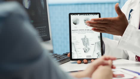 médico de cabecera señalando una ilustración para explicar el diagnóstico a la mujer