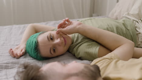 man touching his girlfriend's cheek while lying on the bed at home 1