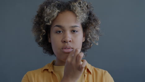 young woman with neutral expression and hand gesture