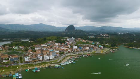 Drone-Flies-Toward-Popular-Tourist-Town-of-Guatape-with-Piedra-del-Penol-in-Background