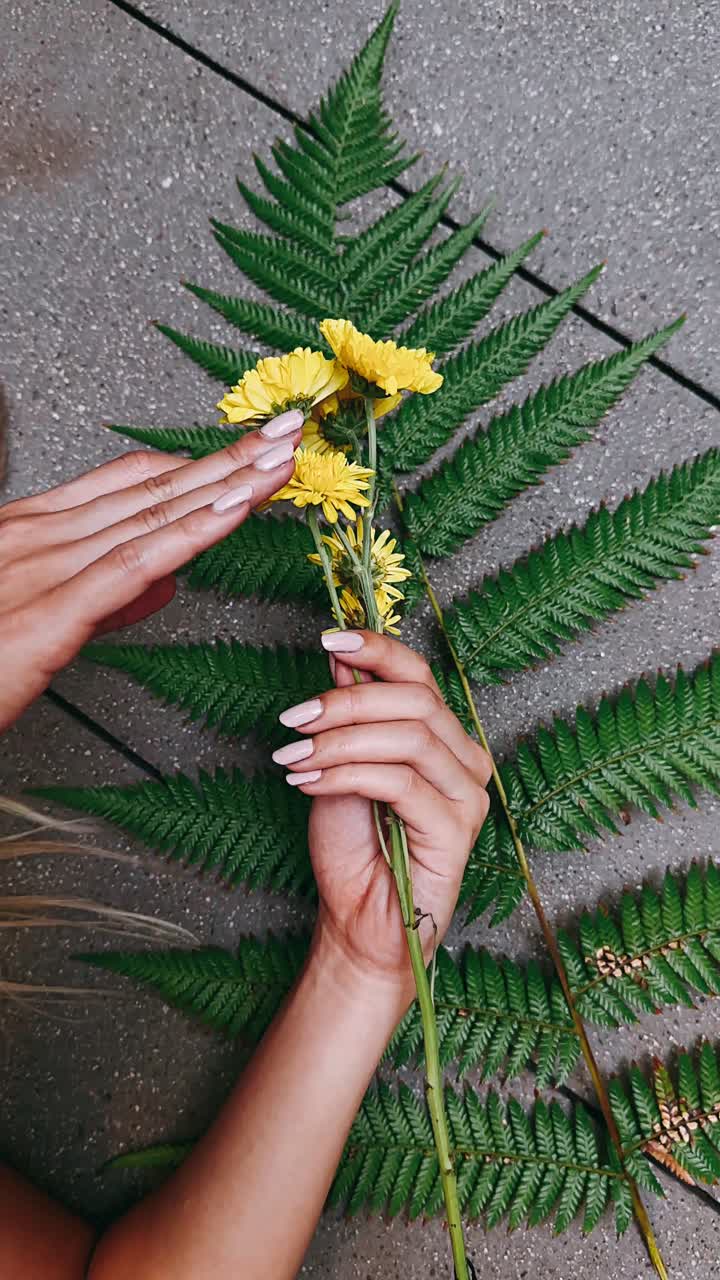 mãos de mulher segurando flores com unhas cor-de-rosa clara