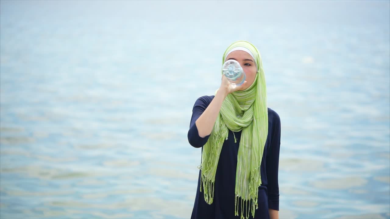 Woman Drinking Water at the Beach