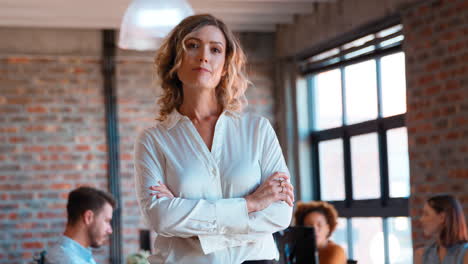 Portrait-Of-Serious-Businesswoman-In-Office-With-Colleagues-Working-In-Background