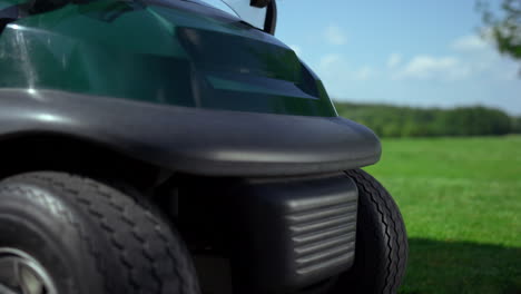 el campo de golf está vacío afuera. las ruedas de los neumáticos del coche de golf están en la hierba.