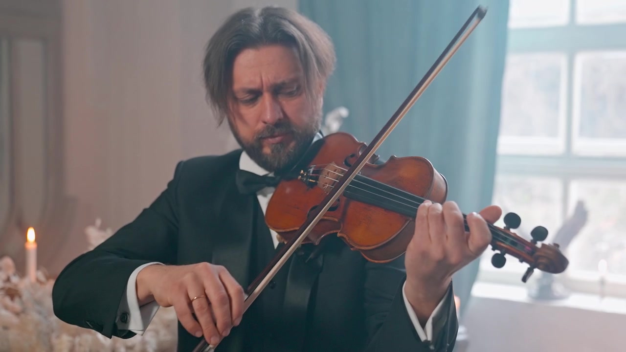 Elegante uomo in smoking che suona il violino classico al chiuso