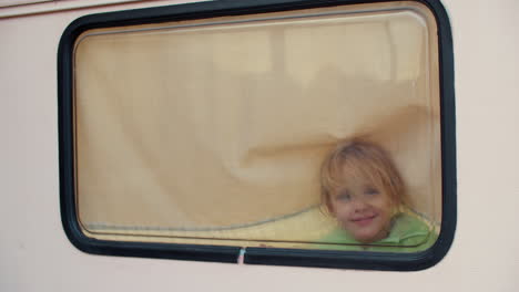 girl finger painting on window in van