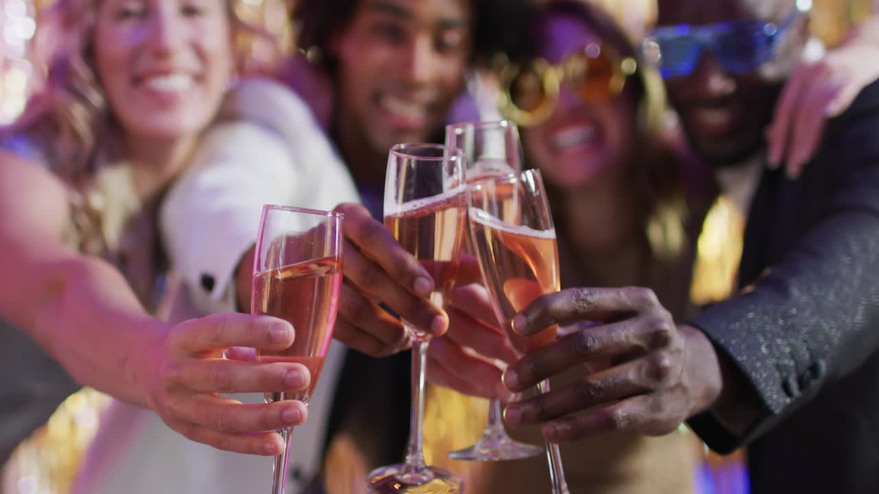 Video portrait of four happy diverse friends toasting with glasses of champagne at a nightclub
