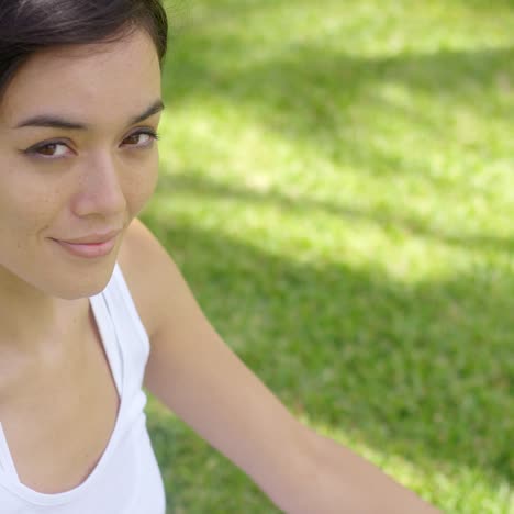 Serene-young-woman-meditating-on-a-green-lawn