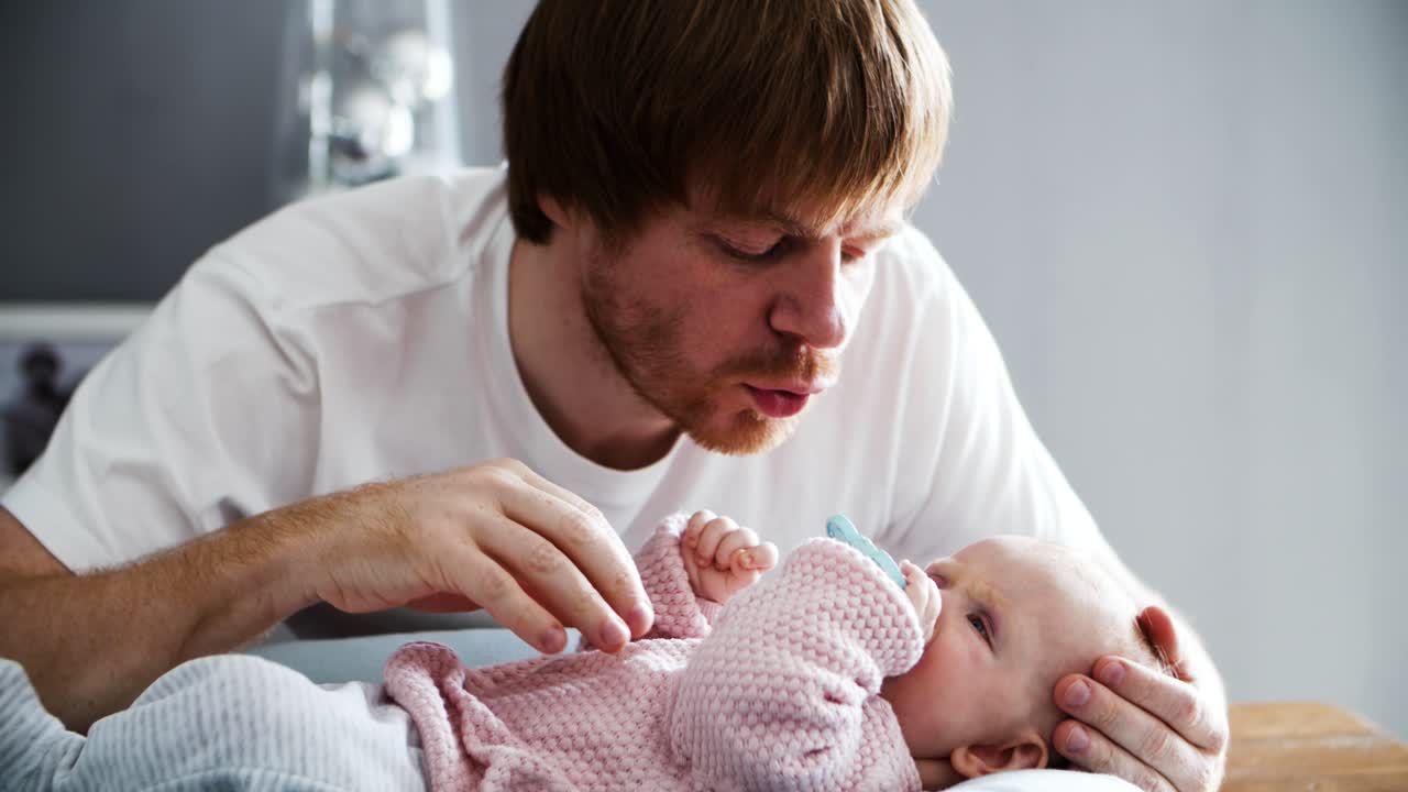Happy peaceful dad soothing baby daughter with toy