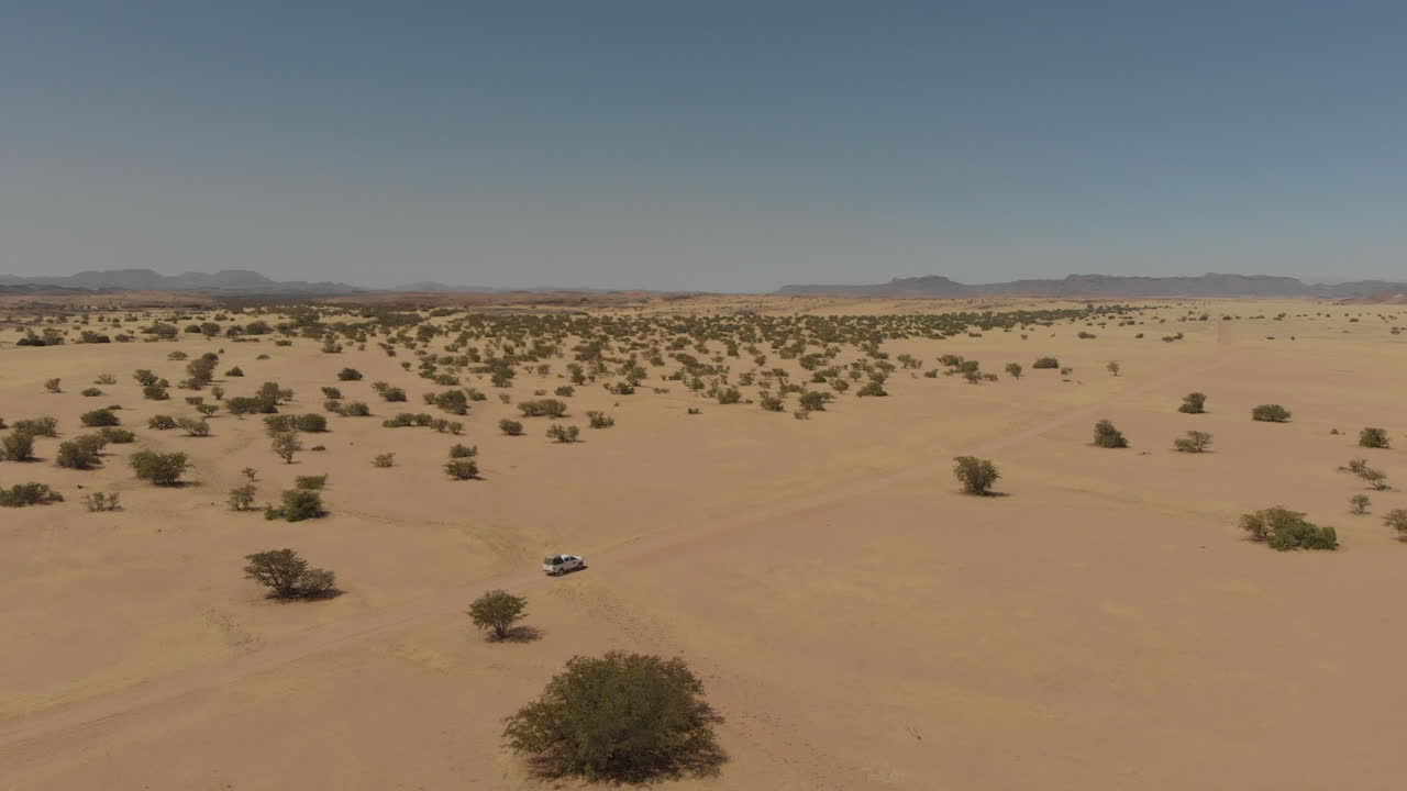 disparo aéreo distante de un vehículo conduciendo solo por el desierto