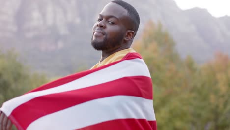 Retrato-De-Un-Hombre-Afroamericano-Sosteniendo-La-Bandera-De-Estados-Unidos-En-El-Jardín,-Cámara-Lenta