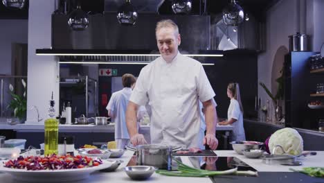 Caucasian-male-chef-working-in-a-restaurant-kitchen,-cooking-and-smiling-at-the-camera