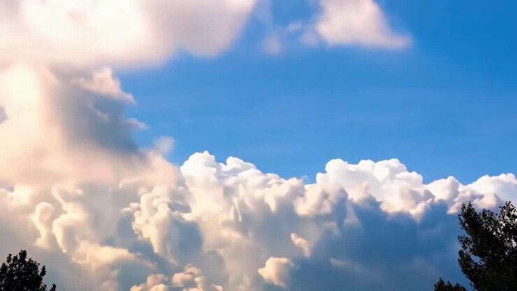 Video of fluffy clouds against a bright blue sky, captured from a low angle, serene and uplifting