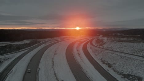 driving through highway in winter landscape with majestic sunrise in background