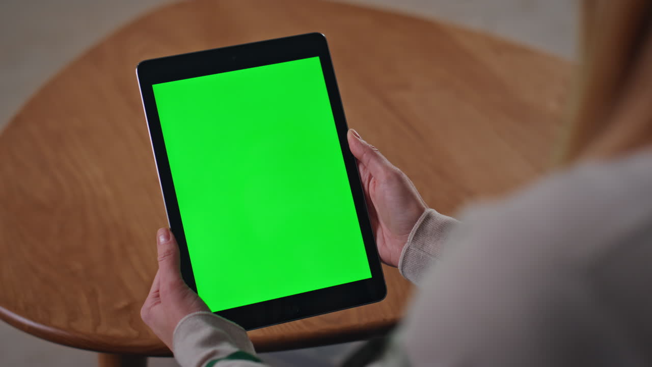 Woman hands holding greenscreen tablet in apartment close up. Girl with mockup