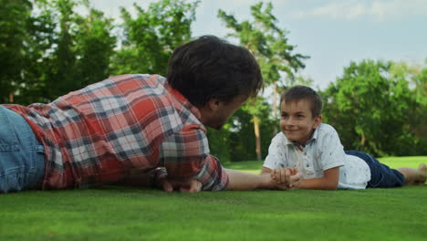 Father-and-son-practising-arm-wrestling-in-meadow.-Boy-winning-competition