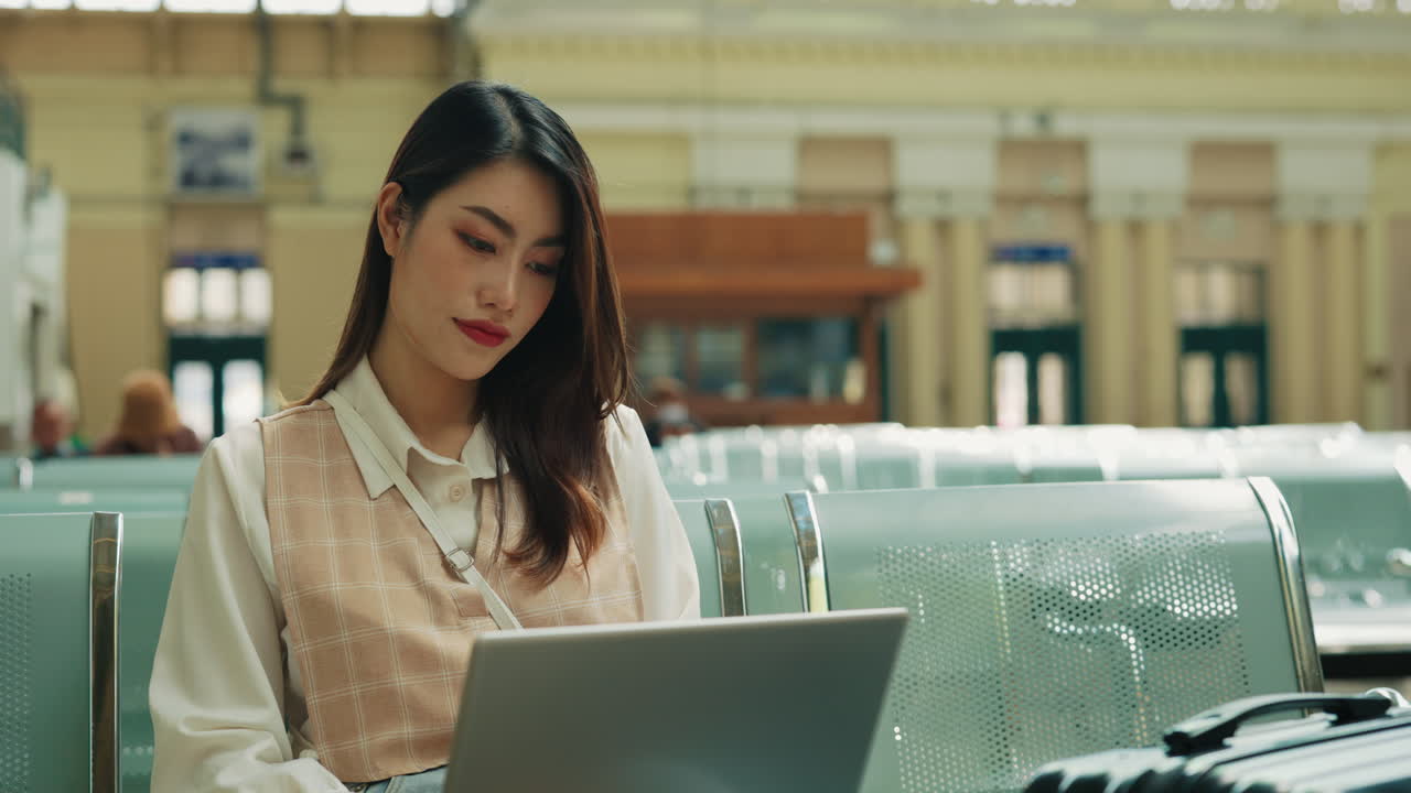 Woman Working on Laptop at Train Station