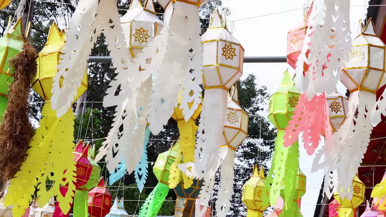 Vibrant paper lanterns and intricate decorations sway gently in the outdoor breeze.