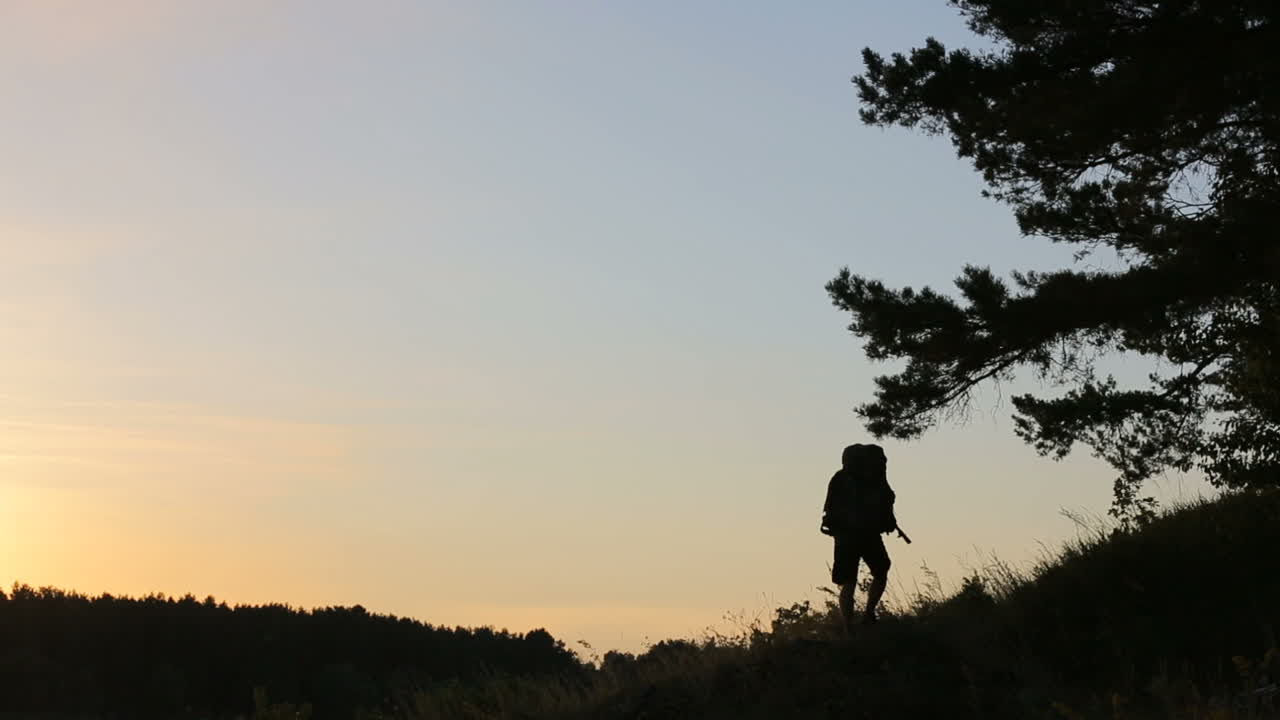 Escursionista che sale sulla collina. Vista posteriore di un escursionista che sale sulla collina di sera.