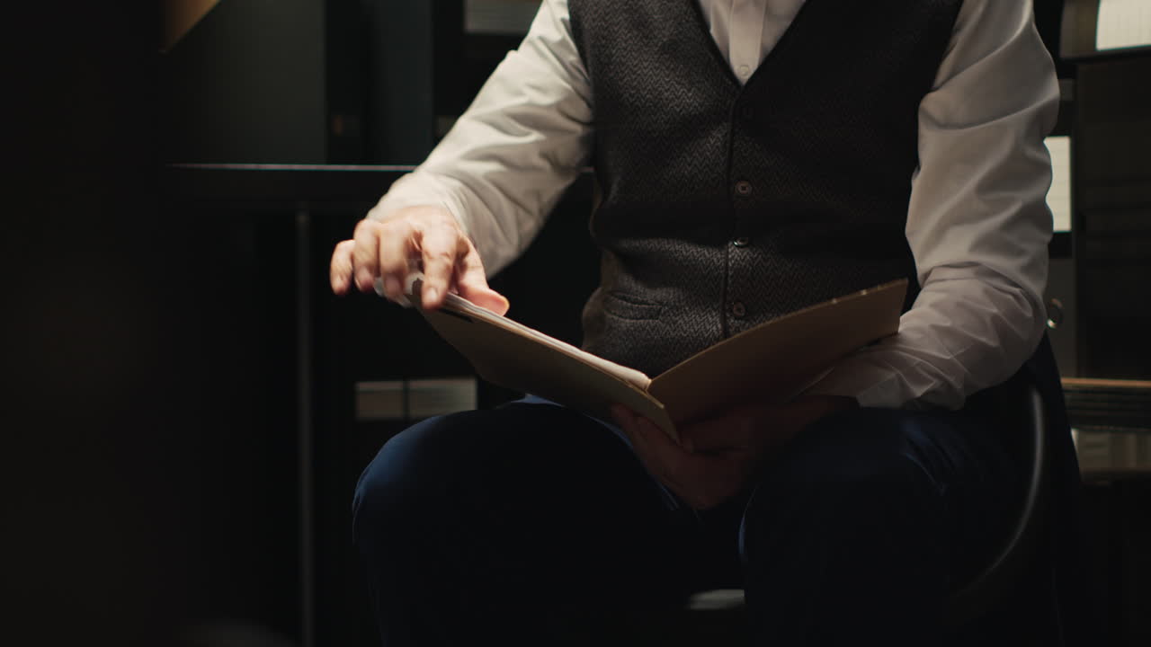 A man is reading a folder indoors